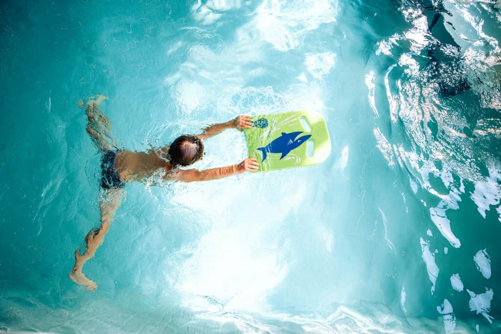 A child practises swimming with a kickboard during a swimming lesson aimed at promoting water safety in Brussels.